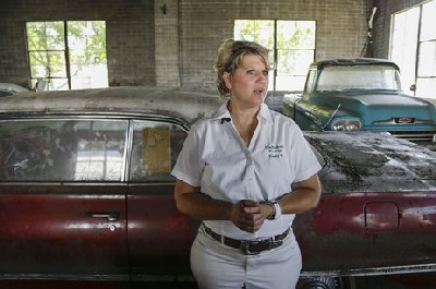 Auctioneer Yvette VanDerBrink in front of a 1963 Chevrolet Impala and a 1958 Cameo pickup truck at the Lambrecht Chevrolet car dealership.